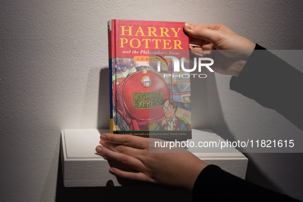 LONDON, UNITED KINGDOM - NOVEMBER 29, 2024: A staff member holds a true first edition of J.K. Rowling's Harry Potter and the Philosopher's S...