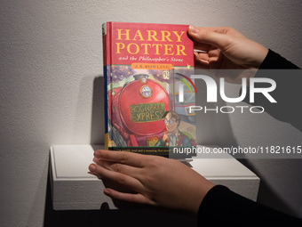 LONDON, UNITED KINGDOM - NOVEMBER 29, 2024: A staff member holds a true first edition of J.K. Rowling's Harry Potter and the Philosopher's S...