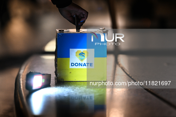 KRAKOW, POLAND - NOVEMBER 29:
A passerby drops a billet into a collection box on the 218th day of the Russian invasion of Ukraine as a few m...