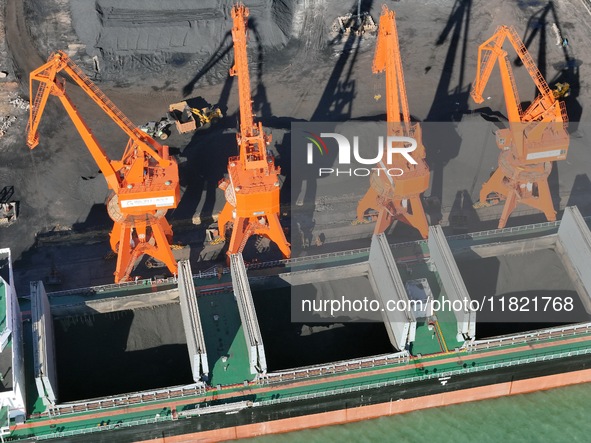 Cranes unload coal from cargo ships at Longkou port area of Yantai Port in East China's Shandong province on November 29, 2024. 