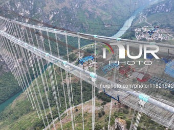 Workers work on the Huajiang Canyon Bridge in Qianxinan, Guizhou province, China, on November 30, 2024. The bridge is a steel girder suspens...