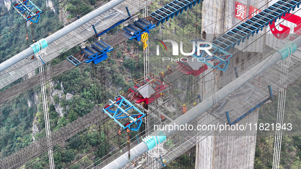 Workers work on the Huajiang Canyon Bridge in Qianxinan, Guizhou province, China, on November 30, 2024. The bridge is a steel girder suspens...