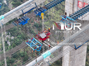 Workers work on the Huajiang Canyon Bridge in Qianxinan, Guizhou province, China, on November 30, 2024. The bridge is a steel girder suspens...