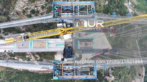 Workers work on the Huajiang Canyon Bridge in Qianxinan, Guizhou province, China, on November 30, 2024. The bridge is a steel girder suspens...