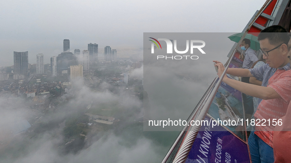 A foreigner takes a photograph of the city of Colombo amid smog and rain from Lotus Tower in Colombo, Sri Lanka, on November 30, 2024. Sri L...