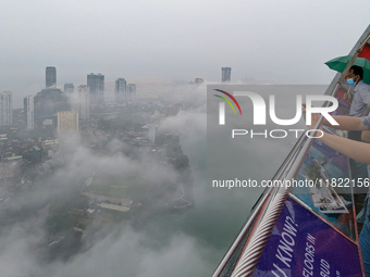 A foreigner takes a photograph of the city of Colombo amid smog and rain from Lotus Tower in Colombo, Sri Lanka, on November 30, 2024. Sri L...