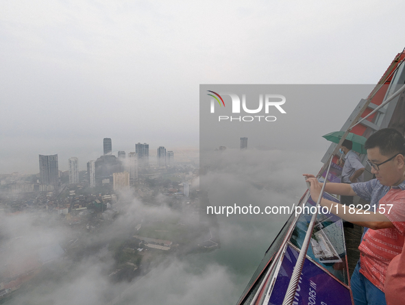 A foreigner takes a photograph of the city of Colombo amid smog and rain from Lotus Tower in Colombo, Sri Lanka, on November 30, 2024. Sri L...