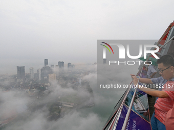 A foreigner takes a photograph of the city of Colombo amid smog and rain from Lotus Tower in Colombo, Sri Lanka, on November 30, 2024. Sri L...