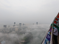 A man wearing a mask with an umbrella looks at the city of Colombo amid smog and rain from Lotus Tower in Colombo, Sri Lanka, on November 30...