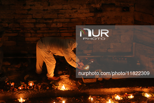 A Nepali Hindu devotee lights oil-fed lamps on the embankment of the Bagmati River in Kathmandu, Nepal, on November 30, 2024, on the occasio...