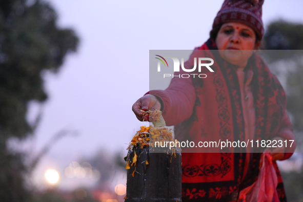 A Nepali Hindu devotee offers ''Sat-bij,'' seven sacred seeds, to a Shivalinga (Idol of Lord Shiva) in the premises of Pashupatinath Temple...