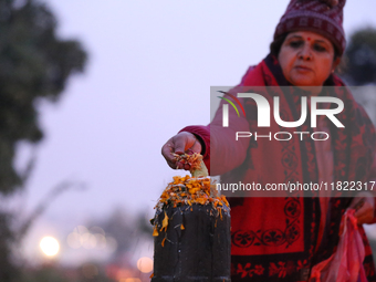 A Nepali Hindu devotee offers ''Sat-bij,'' seven sacred seeds, to a Shivalinga (Idol of Lord Shiva) in the premises of Pashupatinath Temple...