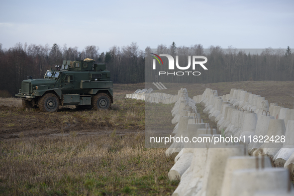 A military vehicle stands guard next to anti-tank concrete fortifications at the Polish-Russian border in Dabrowka, Poland, on November 30,...