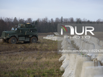 A military vehicle stands guard next to anti-tank concrete fortifications at the Polish-Russian border in Dabrowka, Poland, on November 30,...