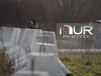 Polish Border Guard members stand guard next to anti-tank concrete fortifications before Polish Prime Minister Donald Tusk's press conferenc...