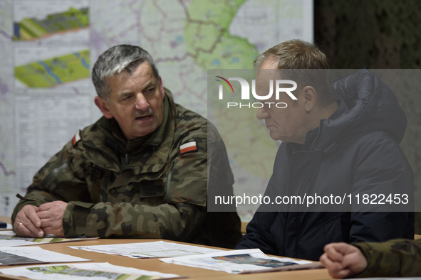 Gen. Marek Wawrzyniak (left) talks to the Polish PM Donald Tusk (right) during a briefing at the Polish-Russian border in Dabrowka, Poland,...