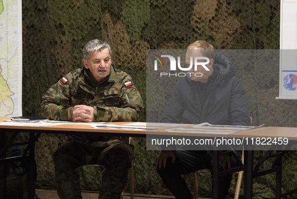 Gen. Marek Wawrzyniak (left) talks to the Polish PM Donald Tusk (right) during a briefing at the Polish-Russian border in Dabrowka, Poland,...