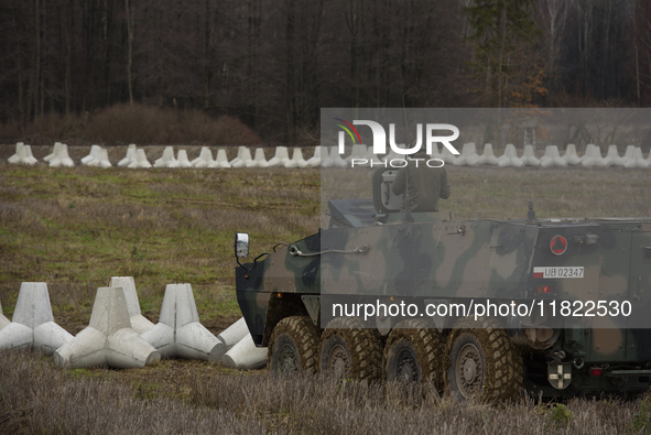 A Polish armed forces vehicle stands guard next to anti-tank concrete fortifications at the Polish-Russian border in Dabrowka, Poland, on No...