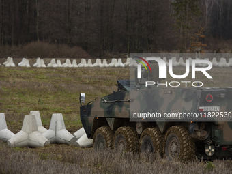 A Polish armed forces vehicle stands guard next to anti-tank concrete fortifications at the Polish-Russian border in Dabrowka, Poland, on No...