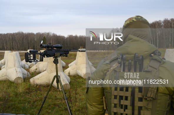 Polish Border Guard members stand guard next to anti-tank concrete fortifications before Polish Prime Minister Donald Tusk's press conferenc...