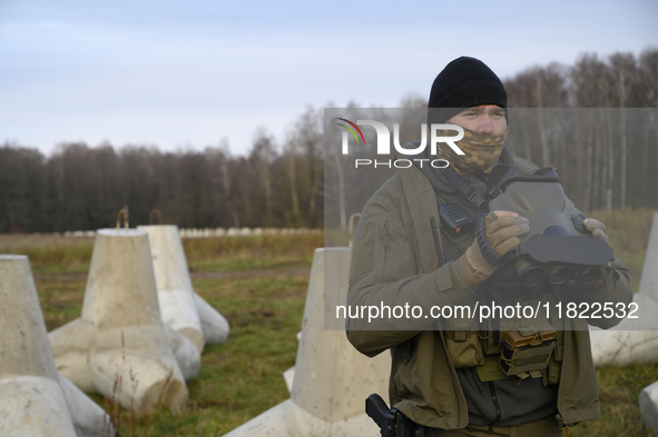 A Polish Border Guard soldier uses thermal vision binoculars as he stands guard next to anti-tank concrete fortifications before Polish Prim...