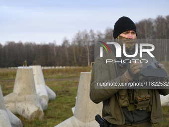 A Polish Border Guard soldier uses thermal vision binoculars as he stands guard next to anti-tank concrete fortifications before Polish Prim...