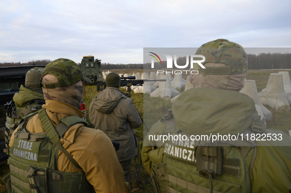 Polish Border Guard members stand guard next to anti-tank concrete fortifications before Polish Prime Minister Donald Tusk's press conferenc...