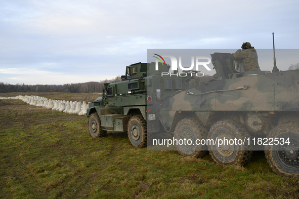 Military vehicles stand guard next to anti-tank concrete fortifications before Polish Prime Minister Donald Tusk's press conference at the P...