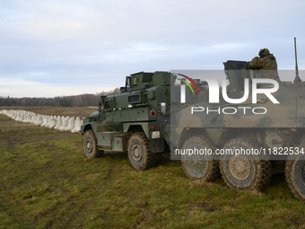 Military vehicles stand guard next to anti-tank concrete fortifications before Polish Prime Minister Donald Tusk's press conference at the P...