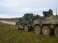 Military vehicles stand guard next to anti-tank concrete fortifications before Polish Prime Minister Donald Tusk's press conference at the P...