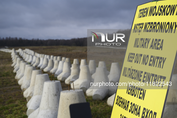 A warning sign lies against anti-tank concrete fortifications at the Polish-Russian border in Dabrowka, Poland, on November 30, 2024. The Ea...