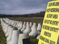 A warning sign lies against anti-tank concrete fortifications at the Polish-Russian border in Dabrowka, Poland, on November 30, 2024. The Ea...