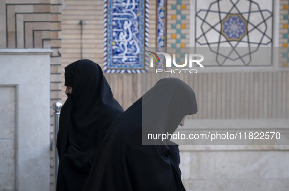 Two veiled Iranian women walk past each other at a mosque in northeastern Tehran, Iran, on November 30, 2024. 