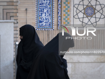 Two veiled Iranian women walk past each other at a mosque in northeastern Tehran, Iran, on November 30, 2024. (