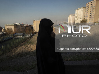 A veiled Iranian woman stands in a residential area in northeastern Tehran, Iran, on November 30, 2024. (