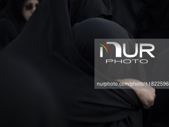 Two veiled Iranian women hug each other while participating in a funeral in northwestern Tehran, Iran, on November 30, 2024. (