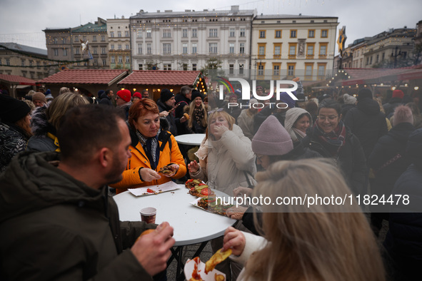 Tourists eat traditional food at Christmas market at the Main Square in Krakow, Poland on Nobember 30th, 2024.  