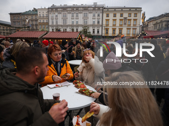 Tourists eat traditional food at Christmas market at the Main Square in Krakow, Poland on Nobember 30th, 2024.  (