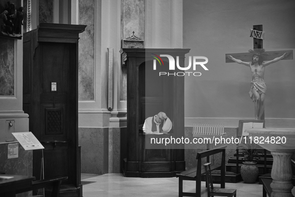 (EDITOR'S NOTE: Image was converted to black and white) A priest seated in a confessional, waiting in solitude in an empty church in Locorot...