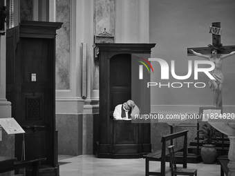 (EDITOR'S NOTE: Image was converted to black and white) A priest seated in a confessional, waiting in solitude in an empty church in Locorot...