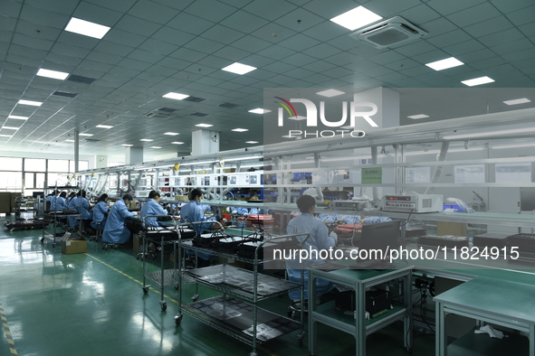 Workers install chips, resistors, and other components on a circuit board in a workshop in Fuyang, China, on November 30, 2024. 