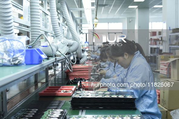 Workers install chips, resistors, and other components on a circuit board in a workshop in Fuyang, Anhui province, China, on November 30, 20...