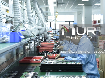 Workers install chips, resistors, and other components on a circuit board in a workshop in Fuyang, Anhui province, China, on November 30, 20...