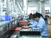 Workers install chips, resistors, and other components on a circuit board in a workshop in Fuyang, Anhui province, China, on November 30, 20...