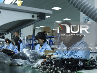 Workers install chips, resistors, and other components on a circuit board in a workshop in Fuyang, Anhui province, China, on November 30, 20...