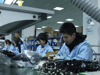 Workers install chips, resistors, and other components on a circuit board in a workshop in Fuyang, Anhui province, China, on November 30, 20...