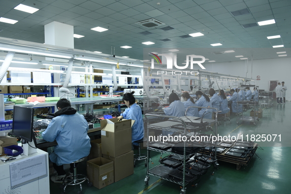 Workers install chips, resistors, and other components on a circuit board in a workshop in Fuyang, Anhui province, China, on November 30, 20...