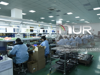 Workers install chips, resistors, and other components on a circuit board in a workshop in Fuyang, Anhui province, China, on November 30, 20...