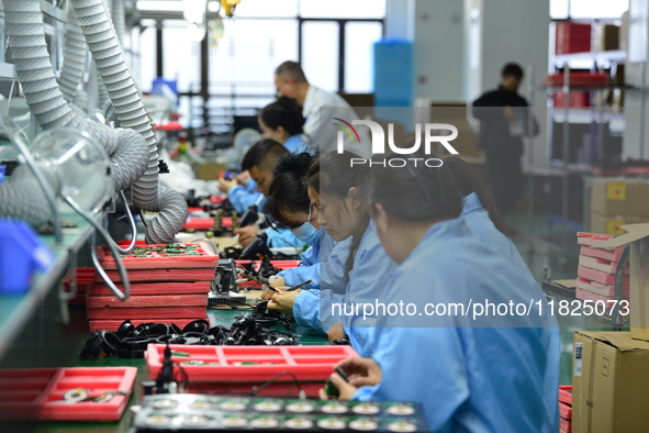 Workers install chips, resistors, and other components on a circuit board in a workshop in Fuyang, Anhui province, China, on November 30, 20...