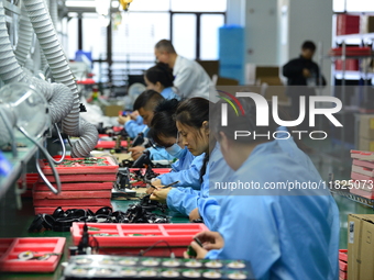 Workers install chips, resistors, and other components on a circuit board in a workshop in Fuyang, Anhui province, China, on November 30, 20...